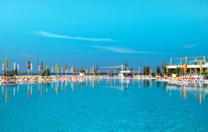 a large pool of blue water with chairs and umbrellas at Arena Grand Kazela Camping Homes in Medulin