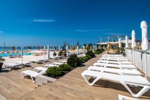 a row of lounge chairs and umbrellas at a beach at Arena Grand Kazela Camping Homes in Medulin