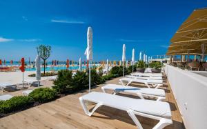 a row of white chaise lounge chairs on a beach at Arena Grand Kazela Camping Homes in Medulin