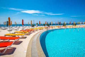 a swimming pool with chairs and umbrellas at Arena Grand Kazela Camping Homes in Medulin