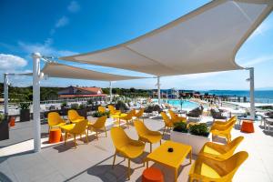 a patio with yellow chairs and tables and a pool at Arena Grand Kazela Camping Homes in Medulin