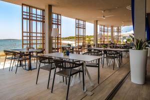 a restaurant with tables and chairs and the ocean at Arena Grand Kazela Camping Homes in Medulin