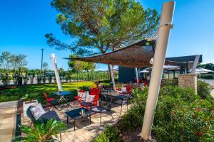 a patio with tables and chairs and a large umbrella at Arena Grand Kazela Camping Homes in Medulin