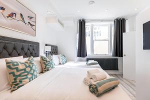 a white bedroom with two beds and a window at The Chapter Hotels - Leisure Inn in London