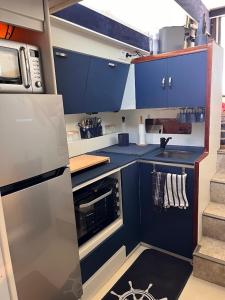 a small kitchen with blue cabinets and a stove at IPANEMA - JOLI BATEAU à QUAI in Sète +29 photos