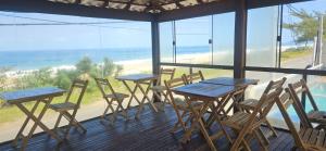 a row of tables and chairs on a balcony with the ocean at Pousada Viva Mar in Saquarema
