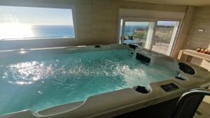 a large bath tub with a view of the ocean at Bubbles Villa Kathisma Beach View Lefkada in Agios Nikitas +10 photos