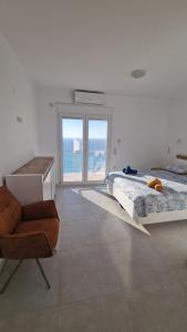 a bedroom with two beds and a chair and a window at Bubbles Villa Kathisma Beach View Lefkada in Agios Nikitas
