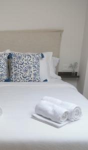 - un lit blanc avec des serviettes et des oreillers dans l'établissement Apartamento AIIA, à Ribadeo