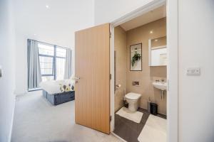 a bathroom with a toilet and a sink and a bed at 2 Bed Oasis London Flat-O2-Excel-Canary Wharf- Shops- Trains -Free Parking,Wifi 500mb & Flex Check In in Woolwich +27 photos