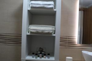 uma casa de banho com uma prateleira com toalhas e um lavatório em Myrina View 3 em Mesochórion mais 11 fotografias