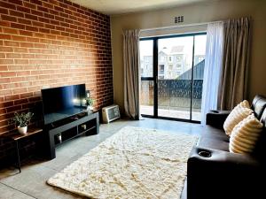 un soggiorno con un divano e un muro di mattoni di Modern Gem Near Mall of Africa! a Kyalami