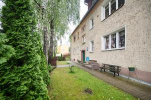 a park bench next to a building with a bush at GM Jagiellończyk in Olsztyn