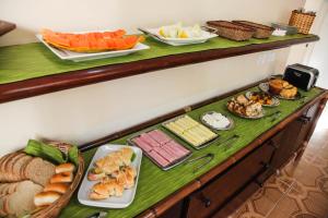 a buffet with different types of food on a table at Pousada Canto da Praça in Bertioga