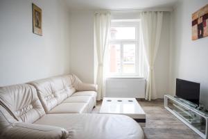 a white living room with a couch and a tv at Downtown Apartments in Prague