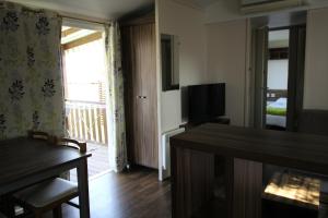a living room with a table and a television at Land's Hause Bungalows par La Conciergerie Française Emplacement 11AA in Pataias