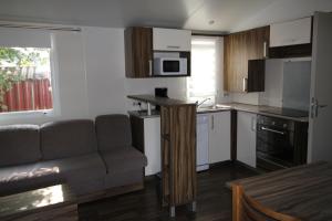 a living room with a couch and a kitchen at Land's Hause Bungalows par La Conciergerie Française Emplacement 11AA in Pataias