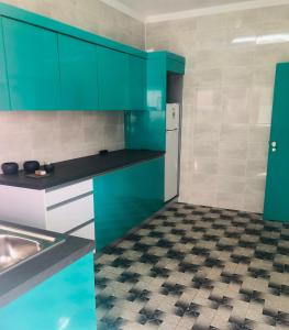 a kitchen with green cabinets and a checkered floor at Casinha do mar in Buarcos +7 photos