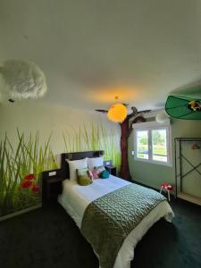 a bedroom with a bed with a tree on the wall at L'évasion Cinégame - Gîte à thème in Diebolsheim