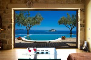 ケリオンにあるKymaros Villasの窓付きのリビングルームからスイミングプールの景色を望めます。