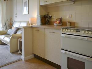 a kitchen with a stove top oven next to a living room at Mr Seal - Uk41452 in Hunstanton