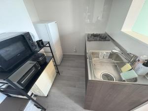 a small kitchen with a sink and a refrigerator at Crest Blue 404-オーシャンフロント! 新築マンション! in Kin