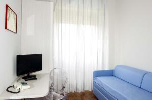 a living room with a blue couch and a television at Hotel Anfora in Castiglione della Pescaia