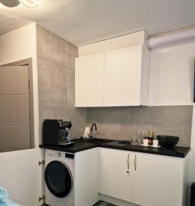 a kitchen with white cabinets and a washing machine at RentA Citywalk Flat in Kaunas