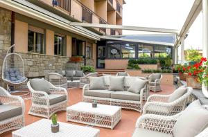 a patio with wicker chairs and couches and tables at Hotel Anfora in Castiglione della Pescaia