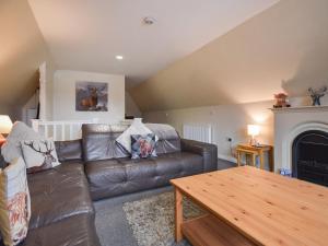 a living room with a leather couch and a table at Ptarmigan Lodge in Balmaha