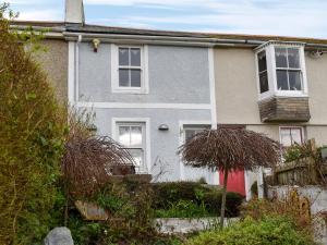 a house with a red door and some bushes at The Cottage in St Ives