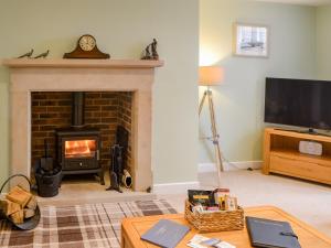 a living room with a fireplace and a tv at Addycombe Cottage in Rothbury