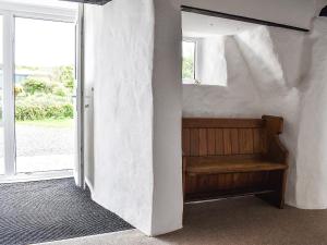 a room with a wooden bench next to a window at Pollards Cottage in Forrabury
