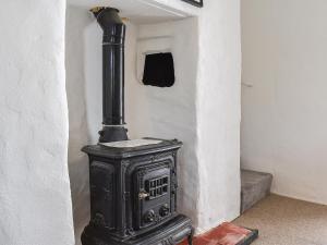 an old black stove in a corner of a room at Pollards Cottage in Forrabury +24 photos