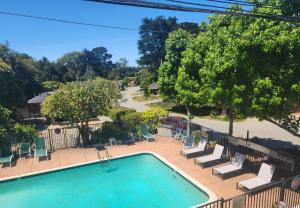 an empty swimming pool with lounge chairs and trees at Carmel River Inn & Cottages in Carmel