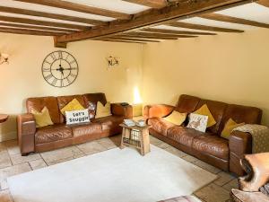 a living room with a couch and a clock on the wall at Old Church Farm in Hinstock