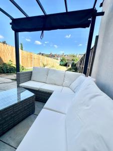 a white couch and a table on a patio at Luxury House in Ilford 21 minute Train journey from Central London in Ilford