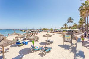 plaża z ludźmi siedzącymi na leżakach i parasolach w obiekcie Viviendas Margarita II w miejscowości Colonia Sant Jordi