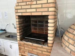 a brick fireplace in a kitchen with a sink at casa com piscina da edi fontes in Guarujá +3 photos