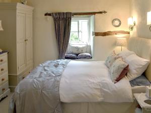 a bedroom with a large white bed and a window at Cragg Cottage in Bouth