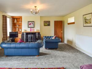 un salon avec deux canapés bleus et une télévision dans l'établissement Southview Cottage, à Cupar