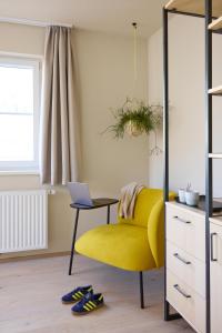 Una silla amarilla en una sala de estar con una computadora portátil en Hotel UND - smart alpine stay, en Schladming