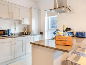 eine Küche mit weißen Schränken und einer Schachtel auf der Theke in der Unterkunft Whinstone House in Craster + 18 Fotos