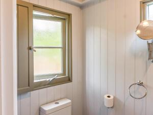 a white bathroom with a window and a toilet at Fig Tree Shepherds Hut - Cottage in Bridport