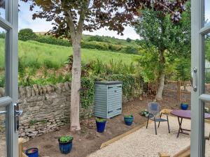 a patio with a table and chairs and a stone wall at Fig Tree Shepherds Hut - Cottage in Bridport