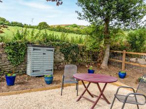 a table and two chairs and a table and a fence at Fig Tree Shepherds Hut - Cottage in Bridport +7 photos