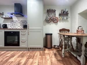 a kitchen with white cabinets and a wooden table at Lyndene Cottage in Moel-tryfan