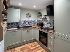 a kitchen with white cabinets and black and white tiles at Lyndene Cottage in Moel-tryfan