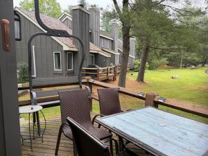 a wooden table and chairs on a deck with a house at Hope's Hideaway in Blakeslee