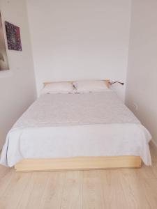 a bed in a white room with a wooden floor at WHITE APARTMENTS free parking self check-inn in Riga